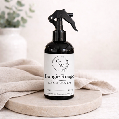 Black spray bottle labeled Bougie Rouge on a wooden surface with a neutral background