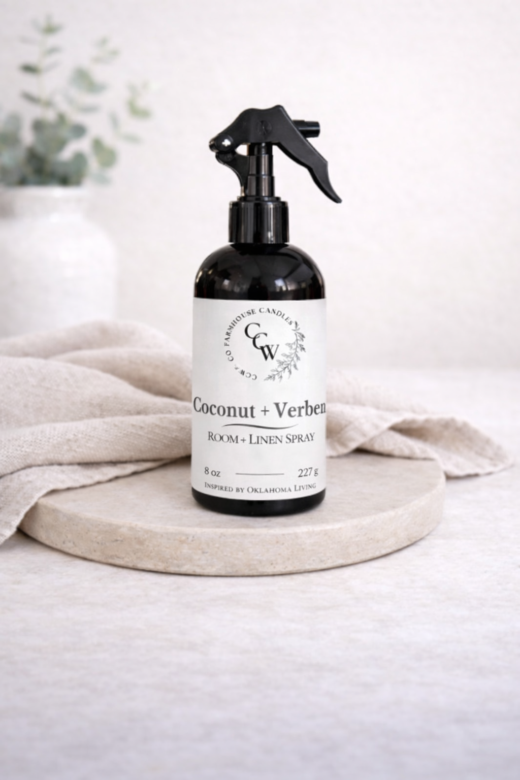 Coconut + Verbena room and linen spray bottle on a light surface with a neutral background