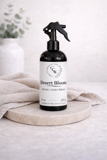 Desert Bloom room and linen spray bottle on a light surface with a neutral background