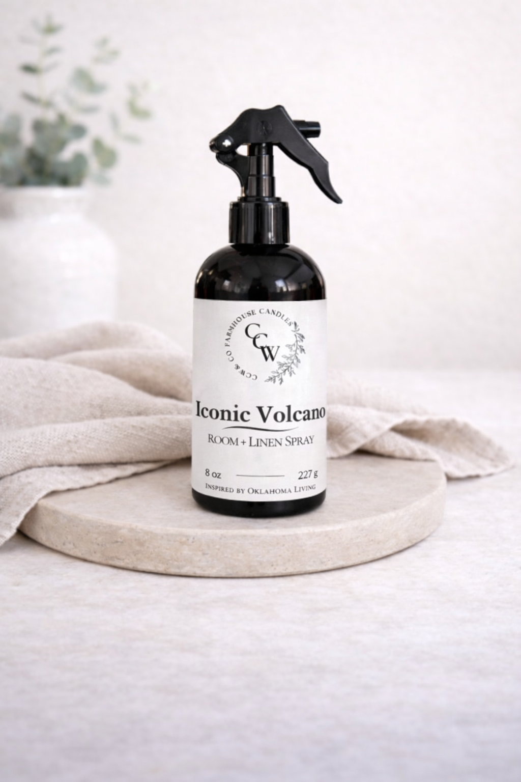 Bottle of 'Iconic Volcano' room linen spray on a white surface with a neutral background