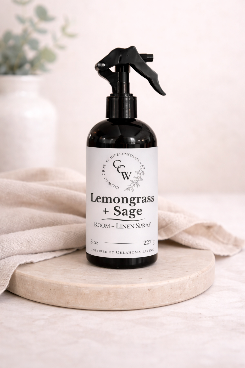 Lemongrass + Sage room and linen spray bottle on a light surface with a neutral background