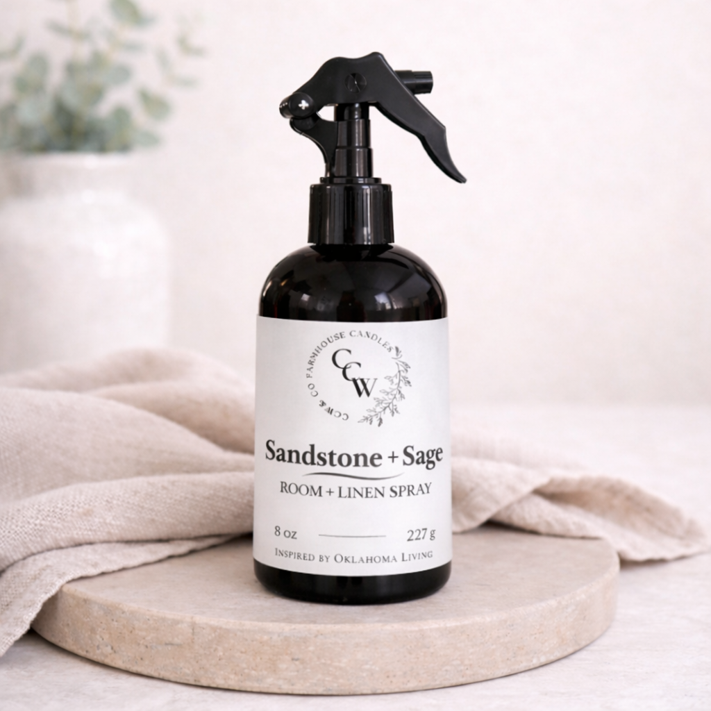 Room spray bottle labeled 'Sandstone + Sage' on a neutral background