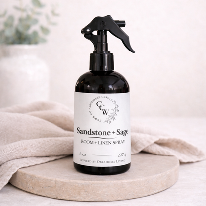 Room spray bottle labeled 'Sandstone + Sage' on a neutral background