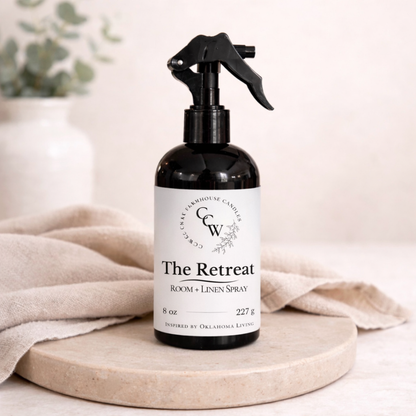 The Retreat room and linen spray bottle on a light surface with a neutral backbackground