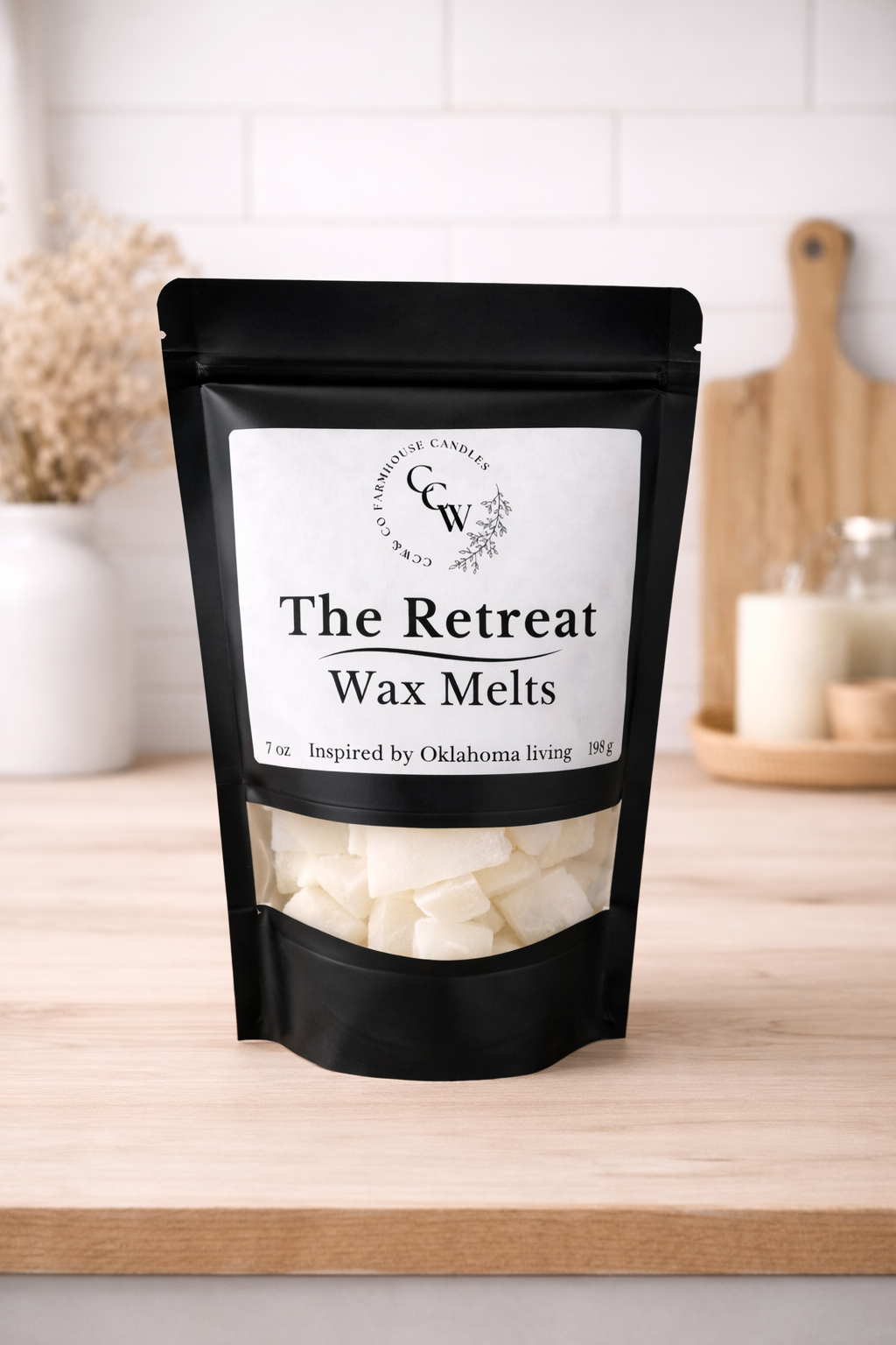 Black resealable pouch of The Retreat wax melts by CCW & Co Farmhouse Candles, featuring a white label and clear window showing hand-poured wax melts, styled on a neutral kitchen countertop.