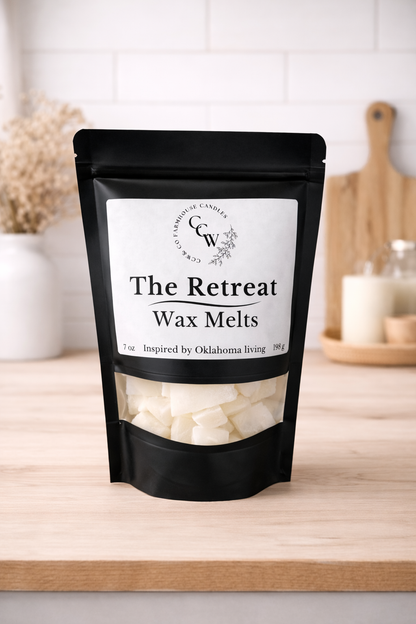 Black resealable pouch of The Retreat wax melts by CCW & Co Farmhouse Candles, featuring a white label and clear window showing hand-poured wax melts, styled on a neutral kitchen countertop.