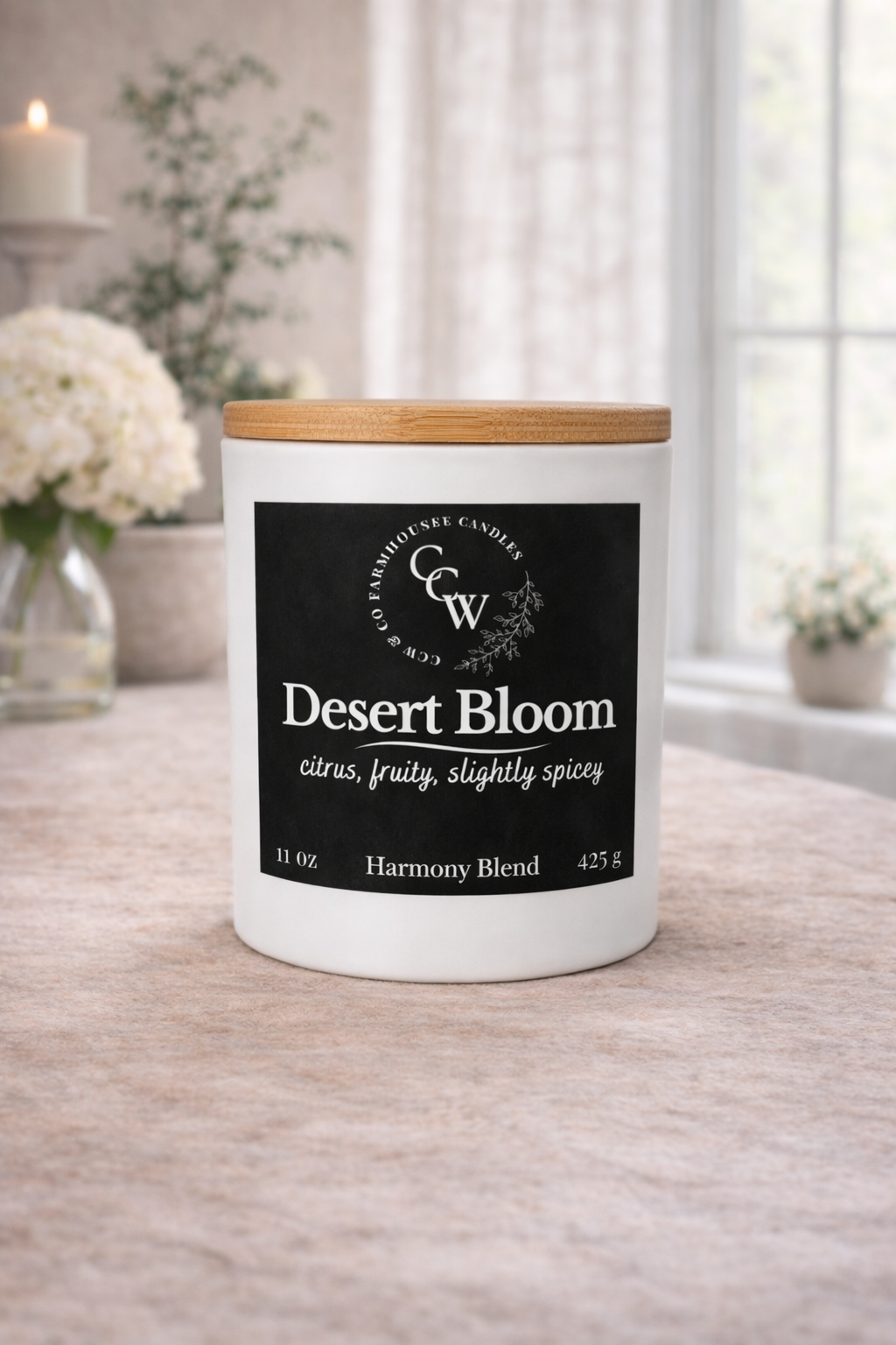 Desert Bloom candle by CCW & Co Farmhouse Candles in a white jar with wooden lid, styled on a neutral tabletop in a light-filled room
