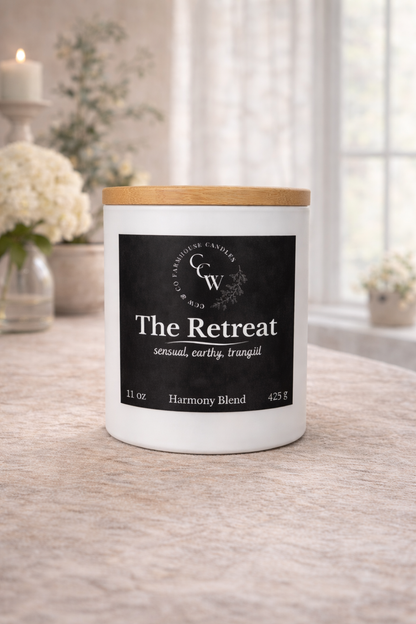 The Retreat candle by CCW & Co Farmhouse Candles in a white jar with wooden lid, styled on a neutral tabletop in soft natural light